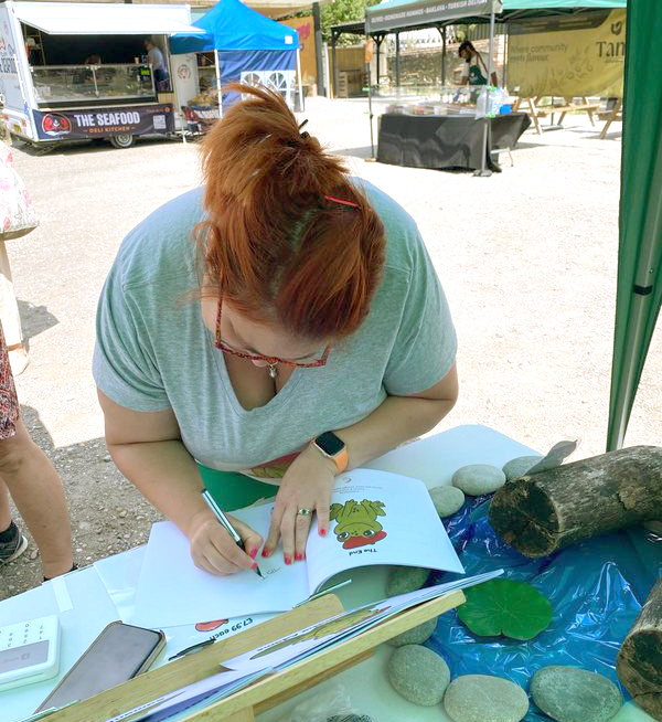 Samantha signing a copy of Horace the Frog at a market stall